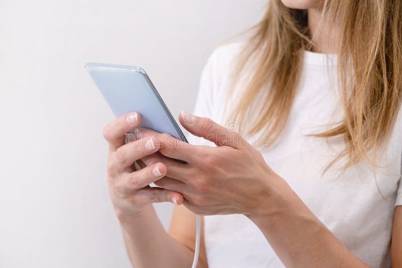 Happy relaxed young woman holding smartphone, looking at cellphone enjoying doing online ecommerce shopping in mobile apps or watching videos. Happy relaxed young woman holding smartphone, looking at cellphone enjoying doing online ecommerce shopping in mobile apps or watching videos.