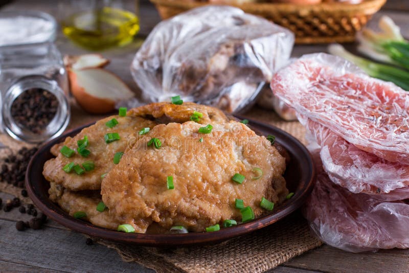 Χοιρινό κρέας schnitzel σε ένα πιάτο και ένα παγωμένο κρέας μπριζολών λαιμών χοιρινού κρέατος στοκ εικόνες Χοιρινό κρέας schnitzel σε ένα πιάτο και ένα παγωμένο κρέας μπριζολών λαιμών χοιρινού κρέατος στοκ εικόνες