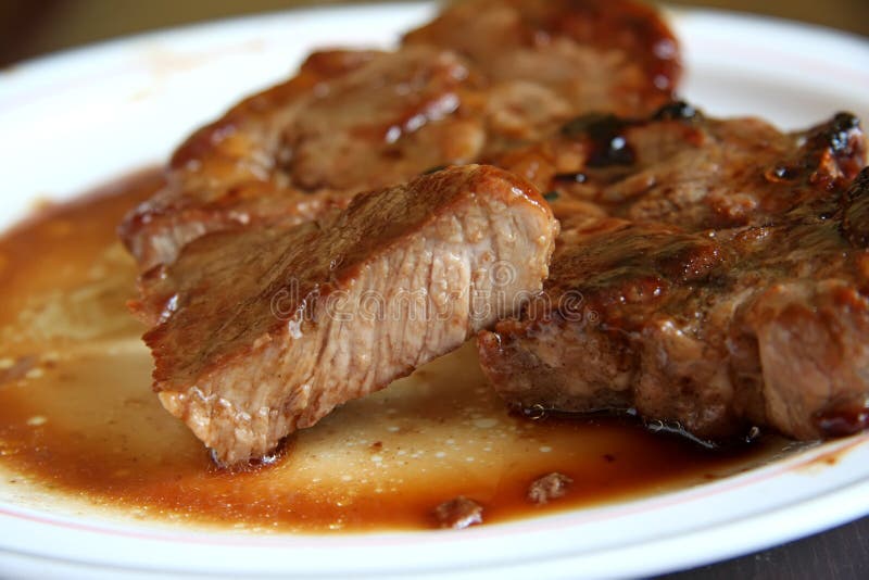 Cooked pork chop on a plate cut medium well done. Cooked pork chop on a plate cut medium well done