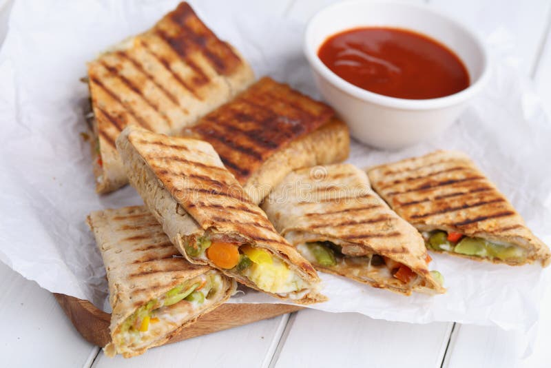 Vegetarian tortilla rolls with cheese and vegetables served with tomato sauce. Vegetarian tortilla rolls with cheese and vegetables served with tomato sauce