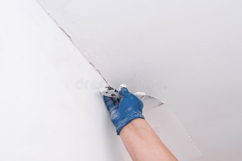 Using a spatula align the wall. A blue-gloved hand. Interior decoration. Using a spatula align the wall. A blue-gloved hand. Interior decoration