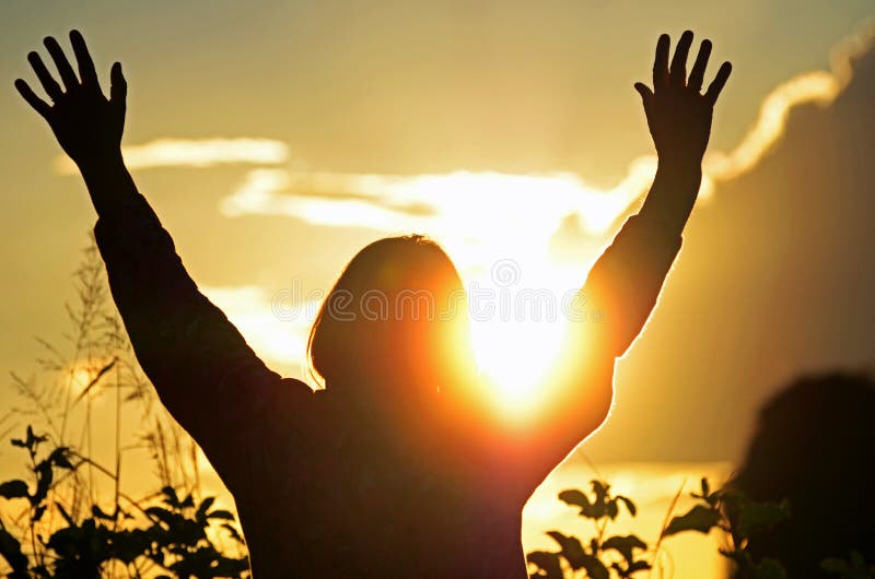 A silhouette portrait set against the beautiful setting sun of late afternoon of a woman lifting her hands high to heaven in praise and worship to Christ resulting in peace, joy and hope. A silhouette portrait set against the beautiful setting sun of late afternoon of a woman lifting her hands high to heaven in praise and worship to Christ resulting in peace, joy and hope.