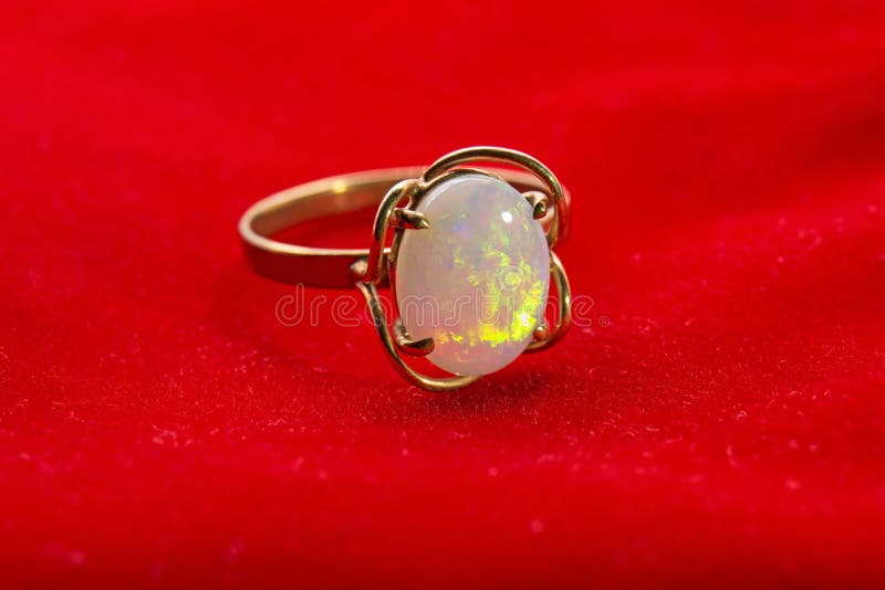 Χρυσό Opal δαχτυλίδι στο κόκκινο βελούδο στοκ εικόνα Χρυσό Opal δαχτυλίδι στο κόκκινο βελούδο στοκ εικόνα