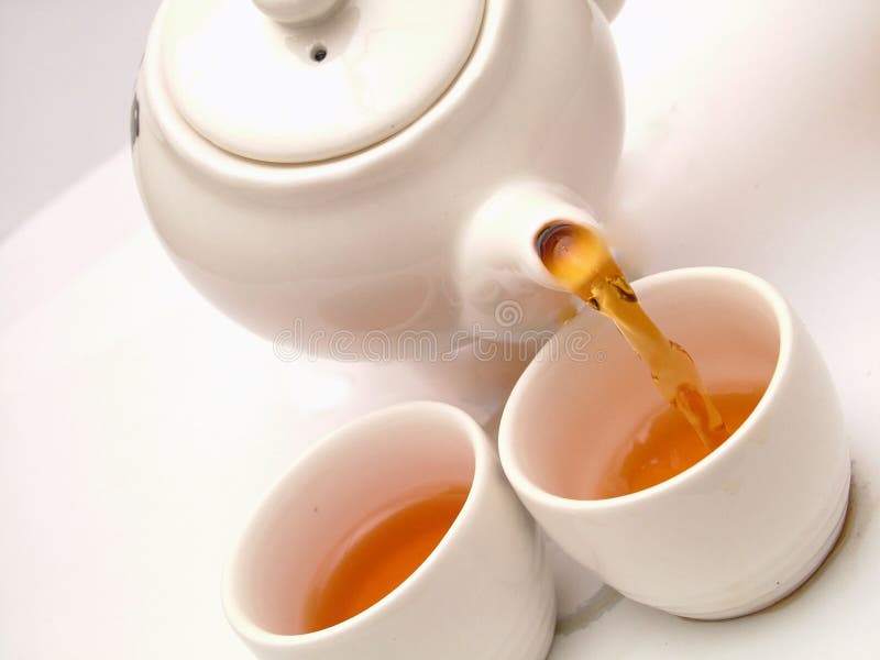 Pouring tea into tea cups. Pouring tea into tea cups