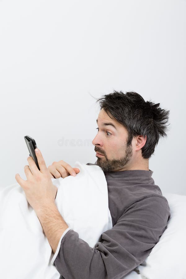 Man with beard lying in a bed with white bedding. Man with beard lying in a bed with white bedding
