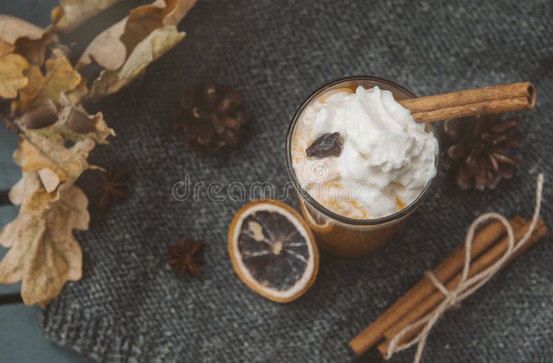 1 Cup pumpkin juice with whipped cream and cinnamon, a slice of dried orange, cones, dry fallen leaves, vegetable juice, top view. 1 Cup pumpkin juice with whipped cream and cinnamon, a slice of dried orange, cones, dry fallen leaves, vegetable juice, top view