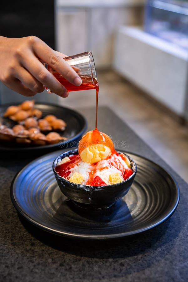 Χύνοντας σάλτσα φραουλών χεριών σε Bingsu, ένα κορεατικό ξυρισμένο επιδόρπιο πάγου με τα γλυκά καλύμματα όπως το παγωτό βανίλιας στοκ εικόνα με δικαίωμα ελεύθερης χρήσης