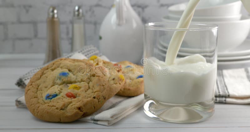 χύτευση γάλακτος σε ένα ποτήρι δίπλα σε ζαχαρώδη μπισκότα