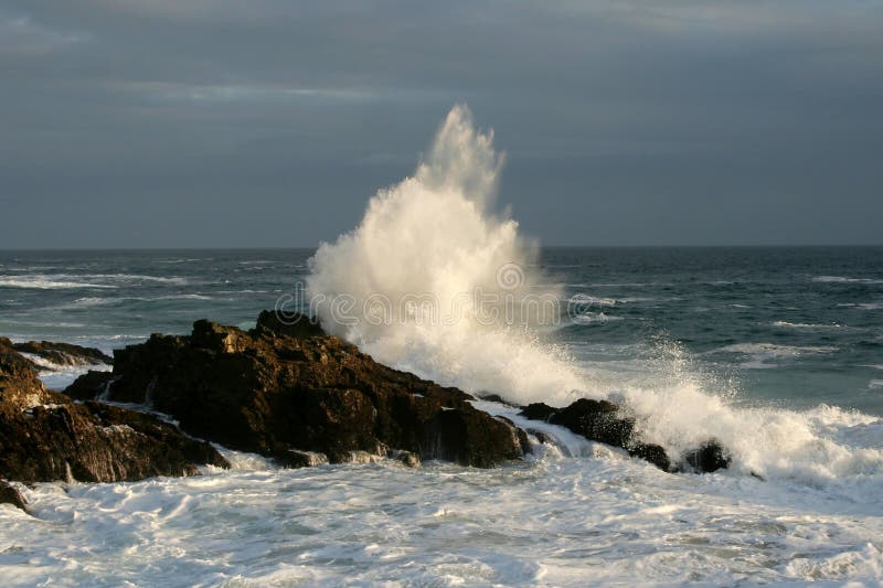 Wave crashing onto rocks creating large spray off South African coastline. Wave crashing onto rocks creating large spray off South African coastline