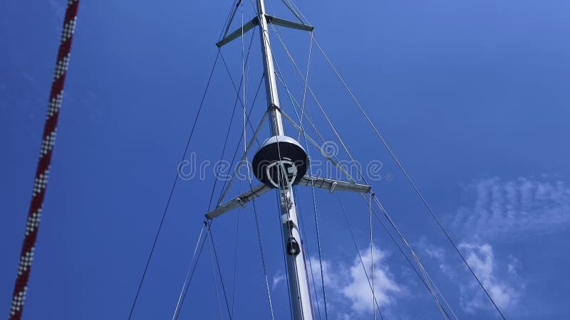 Ψηλός στιβαρός ιστός ενός ιστιοφόρου ξεχωρίζει έντονα από το φωτεινό γαλάζιο ουρανό. απόθεμα βίντεο