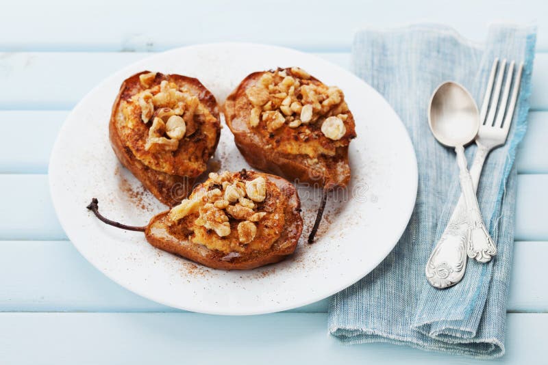 Ψημένα αχλάδια με το ricotta, τα ξύλα καρυδιάς, το μέλι και την κανέλα σε ένα άσπρο πιάτο σε έναν μπλε εκλεκτής ποιότητας πίνακα στοκ φωτογραφίες με δικαίωμα ελεύθερης χρήσης