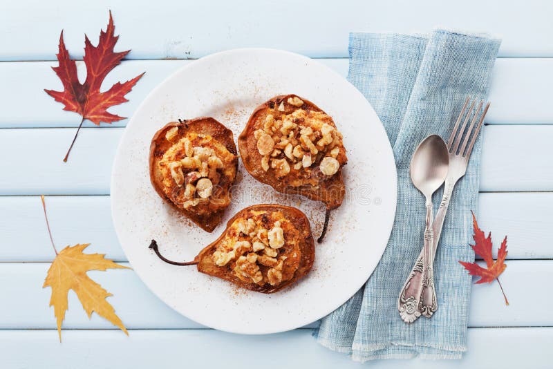 Ψημένα αχλάδια με το ricotta, τα ξύλα καρυδιάς, το μέλι και την κανέλα στο πιάτο σε έναν μπλε εκλεκτής ποιότητας πίνακα άνωθεν Εύ στοκ εικόνες με δικαίωμα ελεύθερης χρήσης