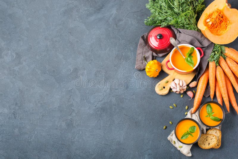 Food and drink, still life, diet and nutrition concept. Seasonal fall autumn roasted orange pumpkin carrot soup with ingredients on a rustic wooden table. Copy space top view cozy kitchen background. Food and drink, still life, diet and nutrition concept. Seasonal fall autumn roasted orange pumpkin carrot soup with ingredients on a rustic wooden table. Copy space top view cozy kitchen background