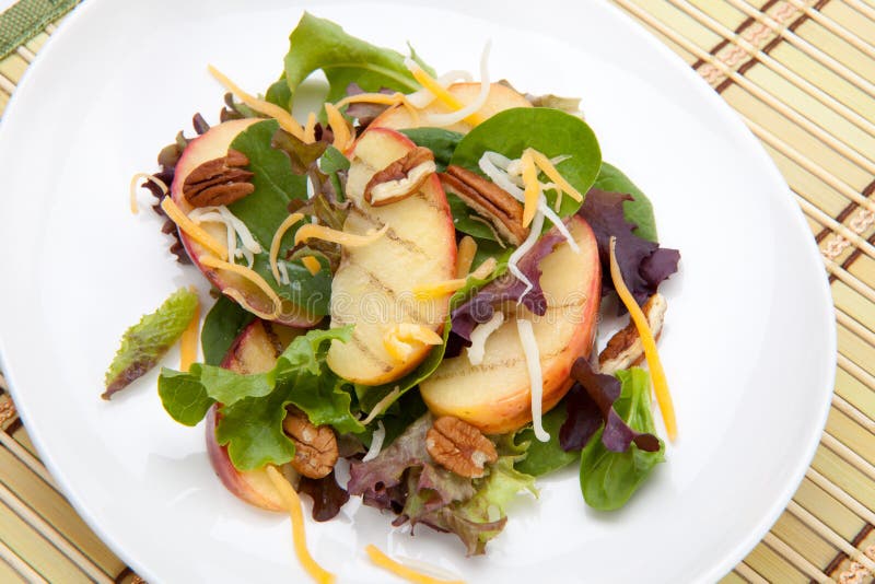 Closeup of salad with grilled apples, baby spinach, pecans, spring mix and chedar cheese served for healthy lunch. Closeup of salad with grilled apples, baby spinach, pecans, spring mix and chedar cheese served for healthy lunch