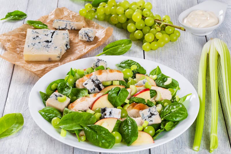 Grilled chicken breast, grapes, celery, spinach, blue cheese and apple salad on a white dish, close-up. Grilled chicken breast, grapes, celery, spinach, blue cheese and apple salad on a white dish, close-up