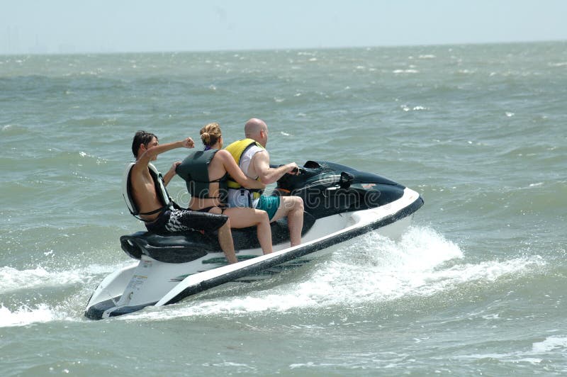 A three person wave runner in the ocean. A family riding a water sport vehicle in the ocean waves. A three person wave runner in the ocean. A family riding a water sport vehicle in the ocean waves.