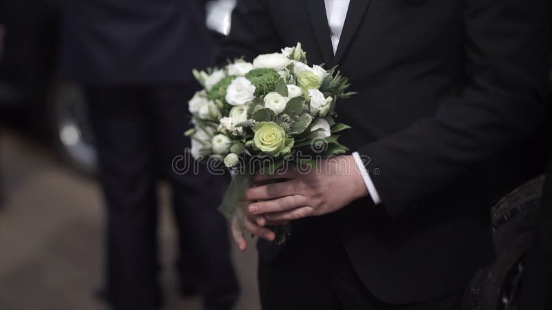 Όμορφα λουλούδια εκμετάλλευσης επιχειρηματιών Νεόνυμφος σε ένα κοστούμι που κρατά μια ανθοδέσμη των λουλουδιών Γαμήλια μπουτονιέρ στοκ εικόνες Όμορφα λουλούδια εκμετάλλευσης επιχειρηματιών Νεόνυμφος σε ένα κοστούμι που κρατά μια ανθοδέσμη των λουλουδιών Γαμήλια μπουτονιέρ στοκ εικόνες