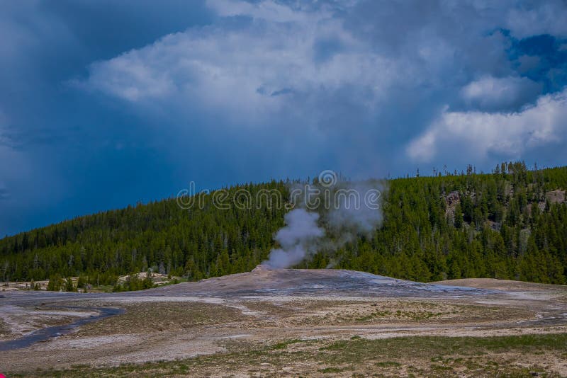 Όμορφη άποψη της παλαιάς πιστής Geyser λεκάνης που βρίσκεται στο εθνικό πάρκο Yellowstone, που περιβάλλεται από τον ατμό με ένα π στοκ φωτογραφία Όμορφη άποψη της παλαιάς πιστής Geyser λεκάνης που βρίσκεται στο εθνικό πάρκο Yellowstone, που περιβάλλεται από τον ατμό με ένα π στοκ φωτογραφία