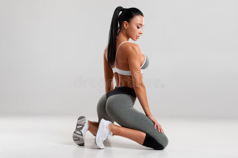 όμορφη γυναίκα αθλητική σέξι γυμνάστρια με πόδια στο γκρι φόντο