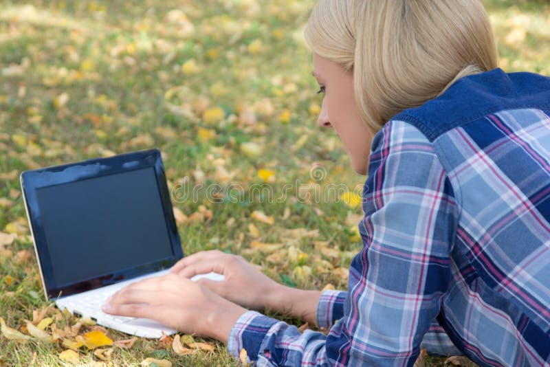 Όμορφη γυναίκα που χρησιμοποιεί το lap-top με την κενή οθόνη στο πάρκο φθινοπώρου στοκ εικόνα με δικαίωμα ελεύθερης χρήσης