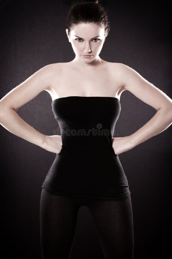 A beautiful woman showing off her hourglass figure in front of a dark background. A beautiful woman showing off her hourglass figure in front of a dark background.