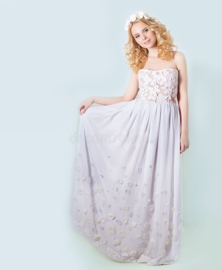 Beautiful lovely gentle elegant young blond woman in a white sundress chiffon and curls, and a wreath of flowers in her hair. Beautiful lovely gentle elegant young blond woman in a white sundress chiffon and curls, and a wreath of flowers in her hair