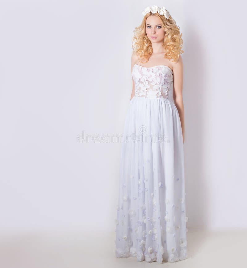 Beautiful lovely gentle elegant young blond woman in a white sundress chiffon and curls, and a wreath of flowers in her hair. Beautiful lovely gentle elegant young blond woman in a white sundress chiffon and curls, and a wreath of flowers in her hair