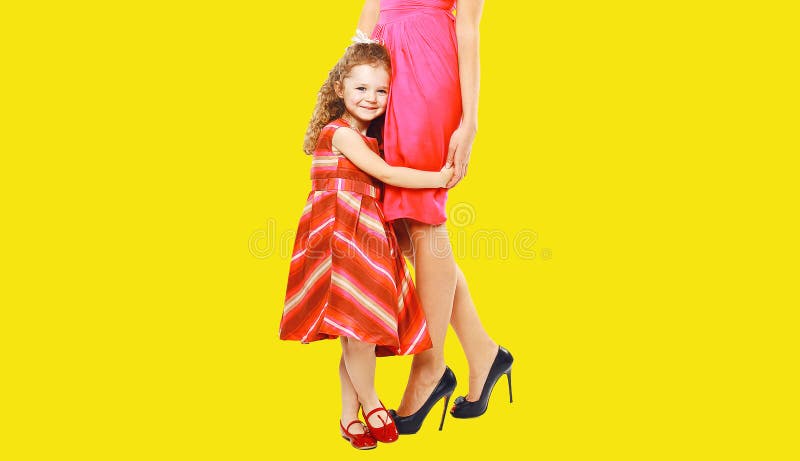 όμορφη μητέρα και μικρό κορίτσι κόρη με φόρεμα κίτρινο φόντο