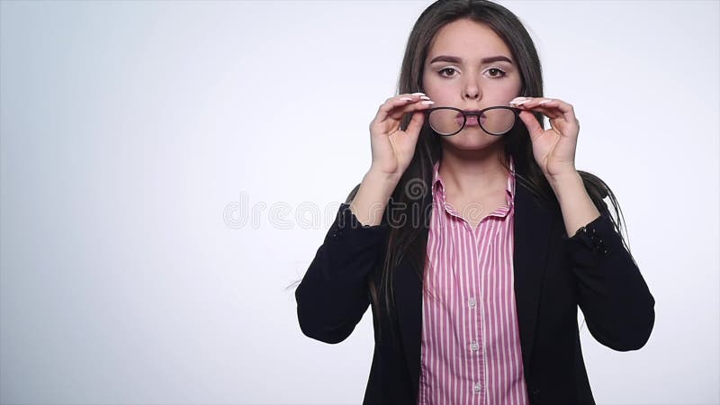 Όμορφη νέα γυναίκα που βγάζει τα γυαλιά στο άσπρο υπόβαθρο
