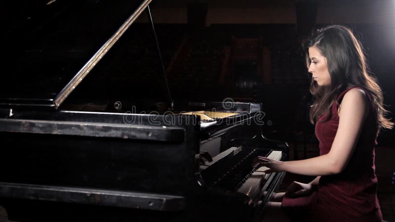 Όμορφη νέα γυναίκα που παίζει το πιάνο στη αίθουσα συναυλιών, πρόβα