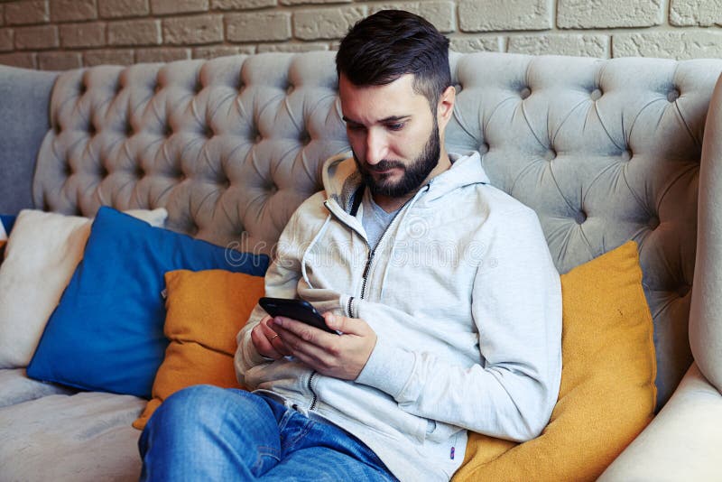 Όμορφη νέα ενήλικη συνεδρίαση ατόμων στον καναπέ στοκ εικόνες Όμορφη νέα ενήλικη συνεδρίαση ατόμων στον καναπέ στοκ εικόνες