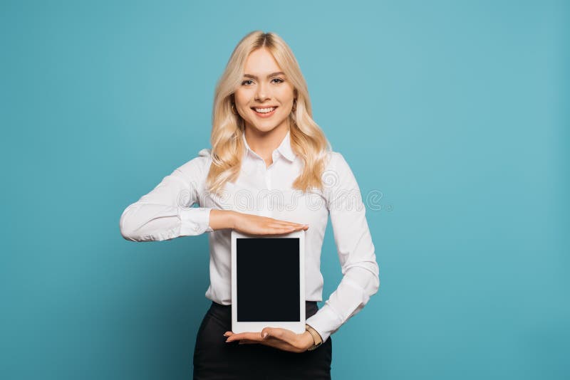 όμορφη ξανθιά επιχειρηματίας που δείχνει smartphone με κενή οθόνη ενώ κοιτάζει την κάμερα στοκ φωτογραφία