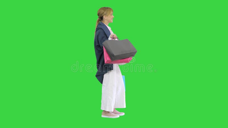 όμορφη χαρούμενη, συναρπαστική, ξανθιά γυναίκα που κρατά τσάντες για ψώνια στο πράσινο κλειδί οθόνης.