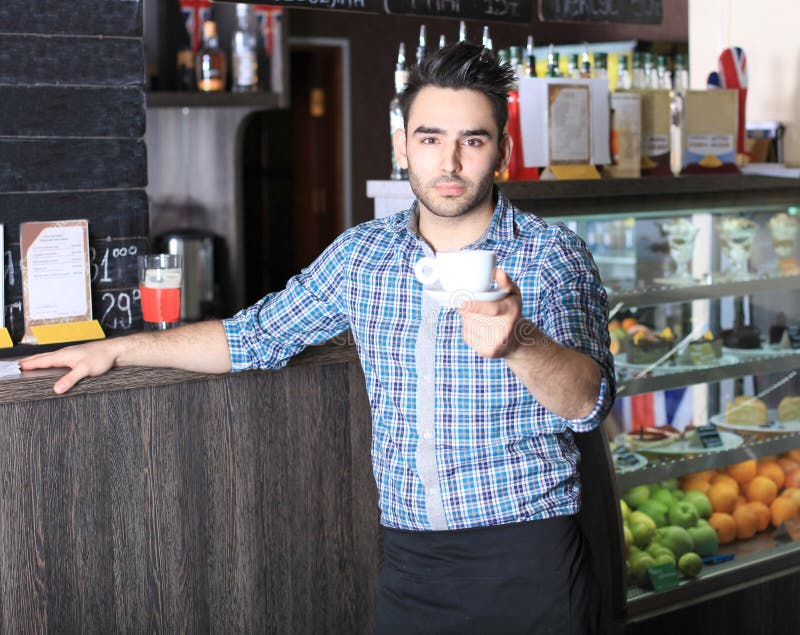 Όμορφο barista που προσφέρει ένα φλιτζάνι του καφέ στοκ εικόνα Όμορφο barista που προσφέρει ένα φλιτζάνι του καφέ στοκ εικόνα