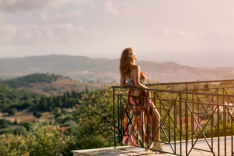Όμορφο θηλυκό σε ένα θερινό φόρεμα σε ένα μπαλκόνι στο υπόβαθρο του ελληνικού τοπίου στοκ εικόνες με δικαίωμα ελεύθερης χρήσης Όμορφο θηλυκό σε ένα θερινό φόρεμα σε ένα μπαλκόνι στο υπόβαθρο του ελληνικού τοπίου στοκ εικόνες με δικαίωμα ελεύθερης χρήσης