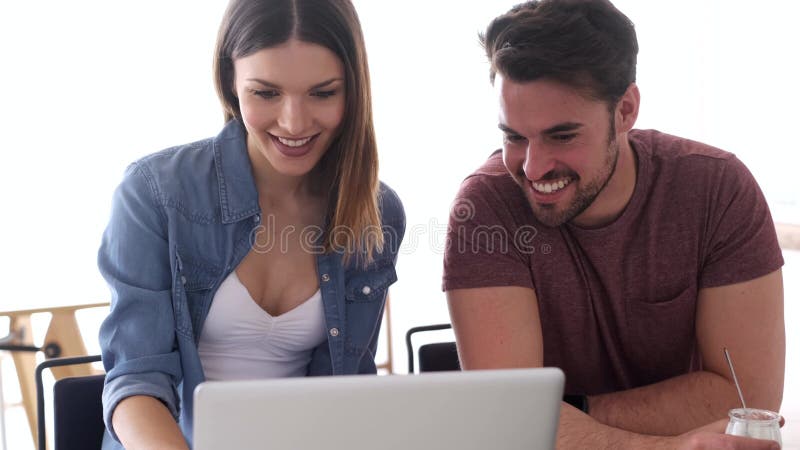 Όμορφο καλό νέο ζεύγος χρησιμοποιώντας το lap-top τους και μιλώντας στην κουζίνα στο σπίτι απόθεμα βίντεο