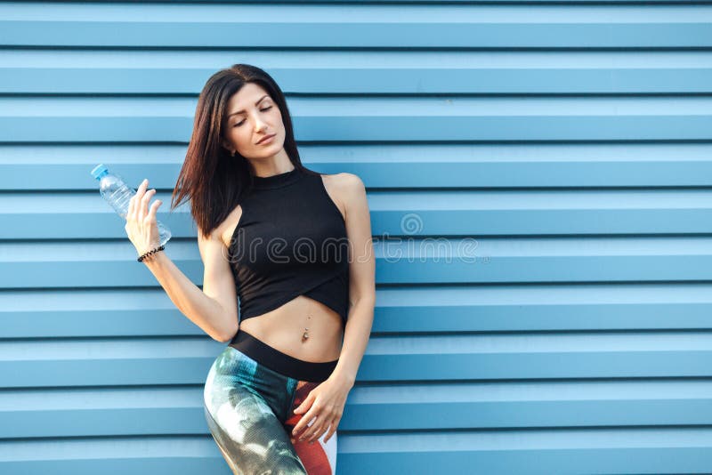 Όμορφο κορίτσι brunette ικανότητας στην κορυφή και οι περικνημίδες με την τοποθέτηση μπουκαλιών νερό, που κρατά την τρίχα της μετ στοκ εικόνα με δικαίωμα ελεύθερης χρήσης Όμορφο κορίτσι brunette ικανότητας στην κορυφή και οι περικνημίδες με την τοποθέτηση μπουκαλιών νερό, που κρατά την τρίχα της μετ στοκ εικόνα με δικαίωμα ελεύθερης χρήσης