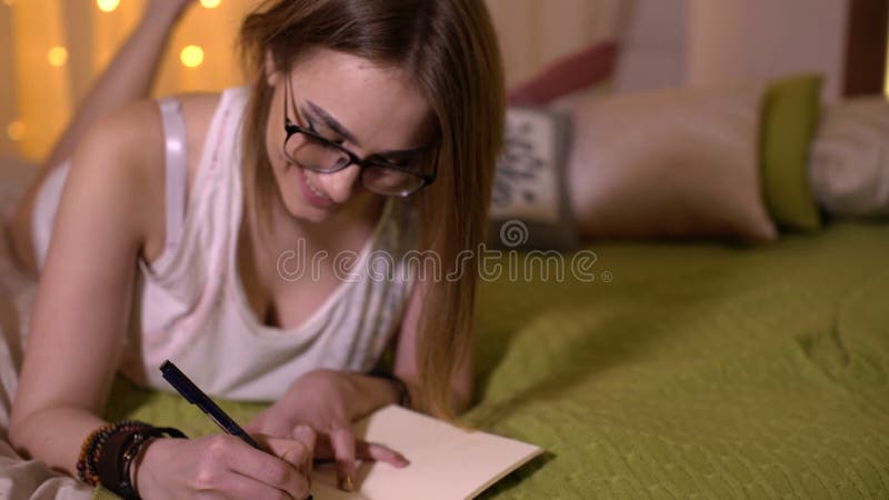 Όμορφο κορίτσι στο nightie που παίρνει τις σημειώσεις