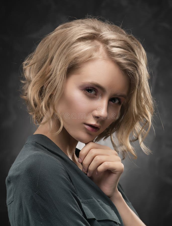 Όμορφο νέο ξανθό κορίτσι με το ατημέλητο hairstyle και το nude makeup, που φορούν ένα πουκάμισο και τα τζιν που θέτουν συναισθημα στοκ εικόνα Όμορφο νέο ξανθό κορίτσι με το ατημέλητο hairstyle και το nude makeup, που φορούν ένα πουκάμισο και τα τζιν που θέτουν συναισθημα στοκ εικόνα