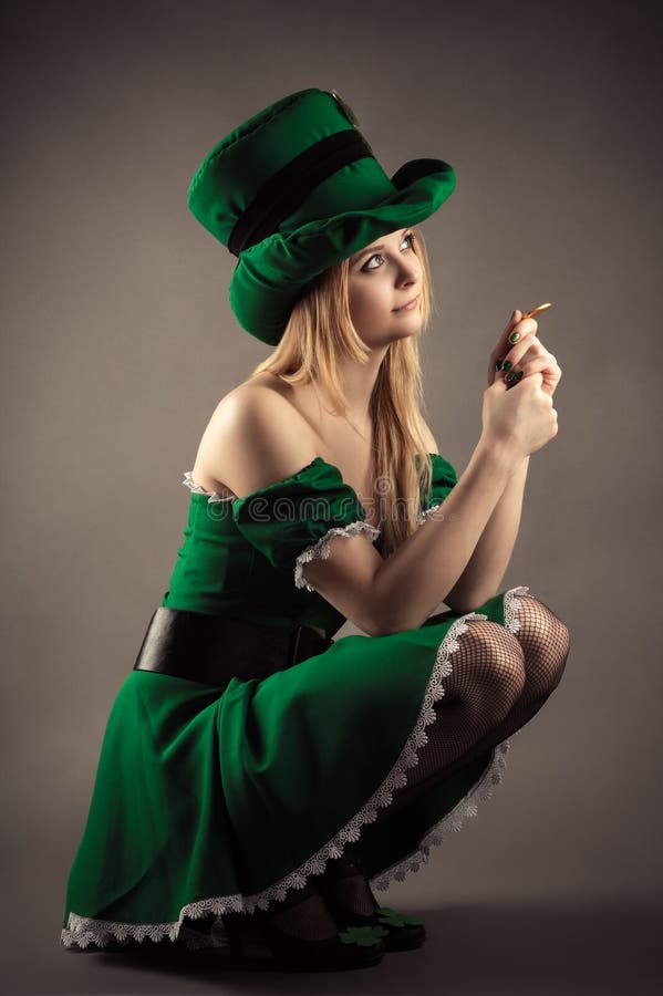 Όμορφο ξανθό κορίτσι στα ενδύματα leprechaun που κάθεται με ένα νόμισμα στοκ φωτογραφία με δικαίωμα ελεύθερης χρήσης Όμορφο ξανθό κορίτσι στα ενδύματα leprechaun που κάθεται με ένα νόμισμα στοκ φωτογραφία με δικαίωμα ελεύθερης χρήσης
