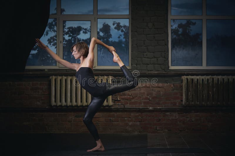 Όμορφο φίλαθλο κατάλληλο asana Natarajasana γιόγκας πρακτικών γυναικών γιόγκη - ο Λόρδος του χορού θέτει στη σκοτεινή αίθουσα στοκ εικόνα Όμορφο φίλαθλο κατάλληλο asana Natarajasana γιόγκας πρακτικών γυναικών γιόγκη - ο Λόρδος του χορού θέτει στη σκοτεινή αίθουσα στοκ εικόνα