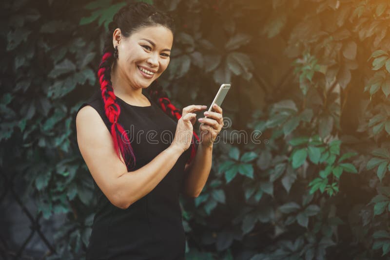 Όμορφο ώριμο ασιατικό θηλυκό πρότυπο με Smartphone υπαίθριο στοκ φωτογραφία Όμορφο ώριμο ασιατικό θηλυκό πρότυπο με Smartphone υπαίθριο στοκ φωτογραφία