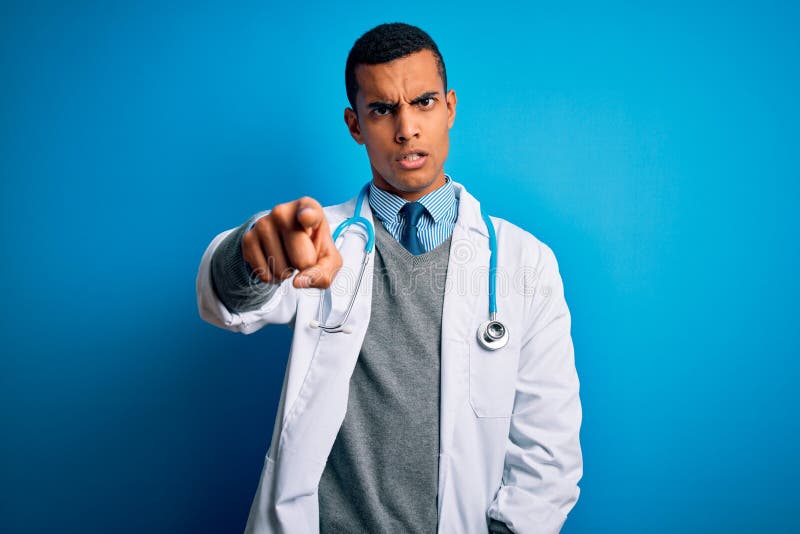 Handsome african american doctor man wearing coat and stethoscope over blue background pointing displeased and frustrated to the camera, angry and furious with you. Handsome african american doctor man wearing coat and stethoscope over blue background pointing displeased and frustrated to the camera, angry and furious with you