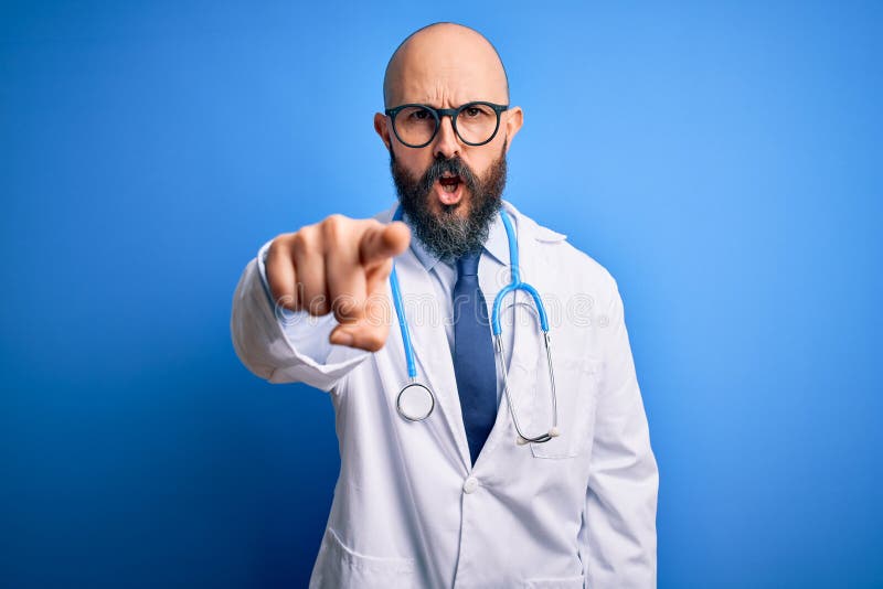 Handsome bald doctor man with beard wearing glasses and stethoscope over blue background pointing displeased and frustrated to the camera, angry and furious with you. Handsome bald doctor man with beard wearing glasses and stethoscope over blue background pointing displeased and frustrated to the camera, angry and furious with you