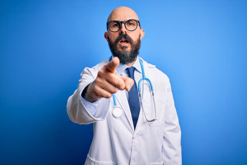 Handsome bald doctor man with beard wearing glasses and stethoscope over blue background pointing displeased and frustrated to the camera, angry and furious with you. Handsome bald doctor man with beard wearing glasses and stethoscope over blue background pointing displeased and frustrated to the camera, angry and furious with you