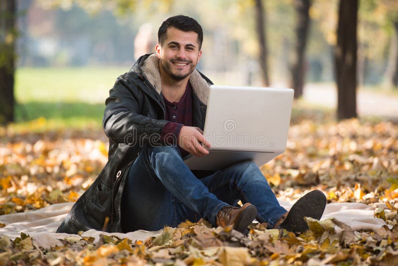 Όμορφος νεαρός άνδρας που χρησιμοποιεί το lap-top σε υπαίθριο στοκ εικόνες Όμορφος νεαρός άνδρας που χρησιμοποιεί το lap-top σε υπαίθριο στοκ εικόνες