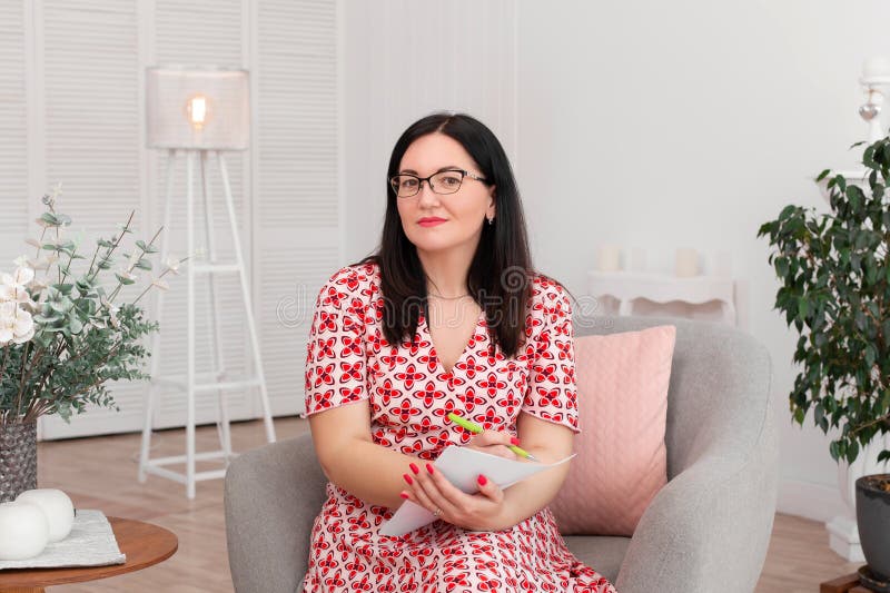 Όμορφος ψυχολόγος γιατρών γυναικών brunette με τα γυαλιά που κάθεται σε ένα φωτεινό γραφείο που χαμογελά και που γράφει σε χαρτί στοκ φωτογραφία με δικαίωμα ελεύθερης χρήσης Όμορφος ψυχολόγος γιατρών γυναικών brunette με τα γυαλιά που κάθεται σε ένα φωτεινό γραφείο που χαμογελά και που γράφει σε χαρτί στοκ φωτογραφία με δικαίωμα ελεύθερης χρήσης