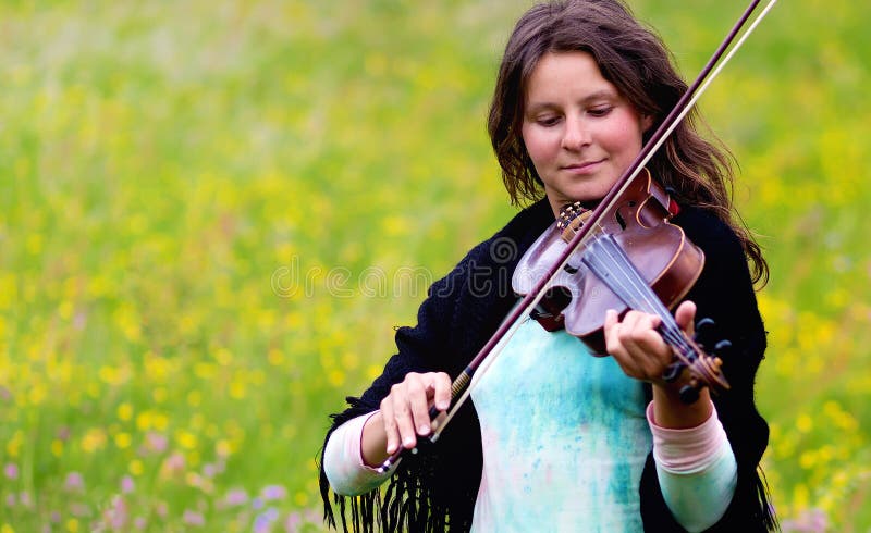 Violinist on a meadow full of flowers, Young girl playing music instrument. Violinist on a meadow full of flowers, Young girl playing music instrument