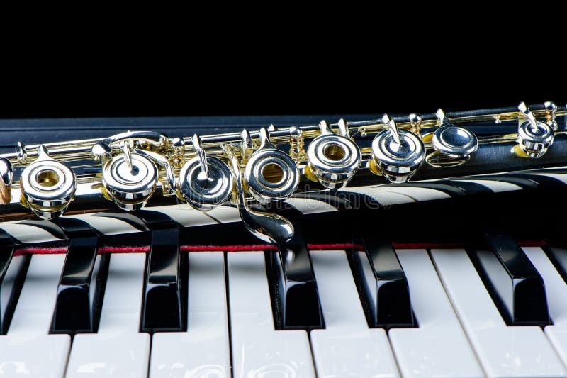 Flute instrument on the piano keyboard on black background. Flute instrument on the piano keyboard on black background