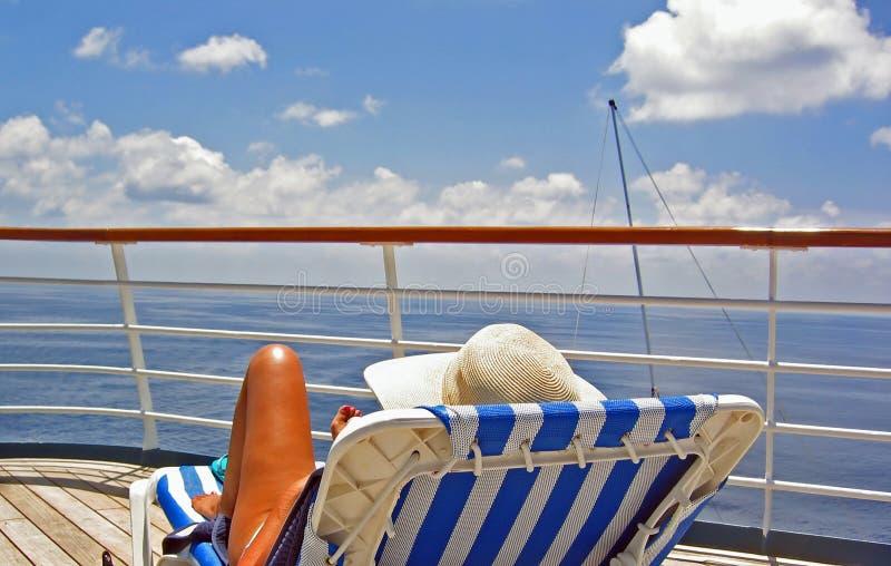 A woman sits on the upper deck of a cruise ship and overlooks the ocean. A woman sits on the upper deck of a cruise ship and overlooks the ocean